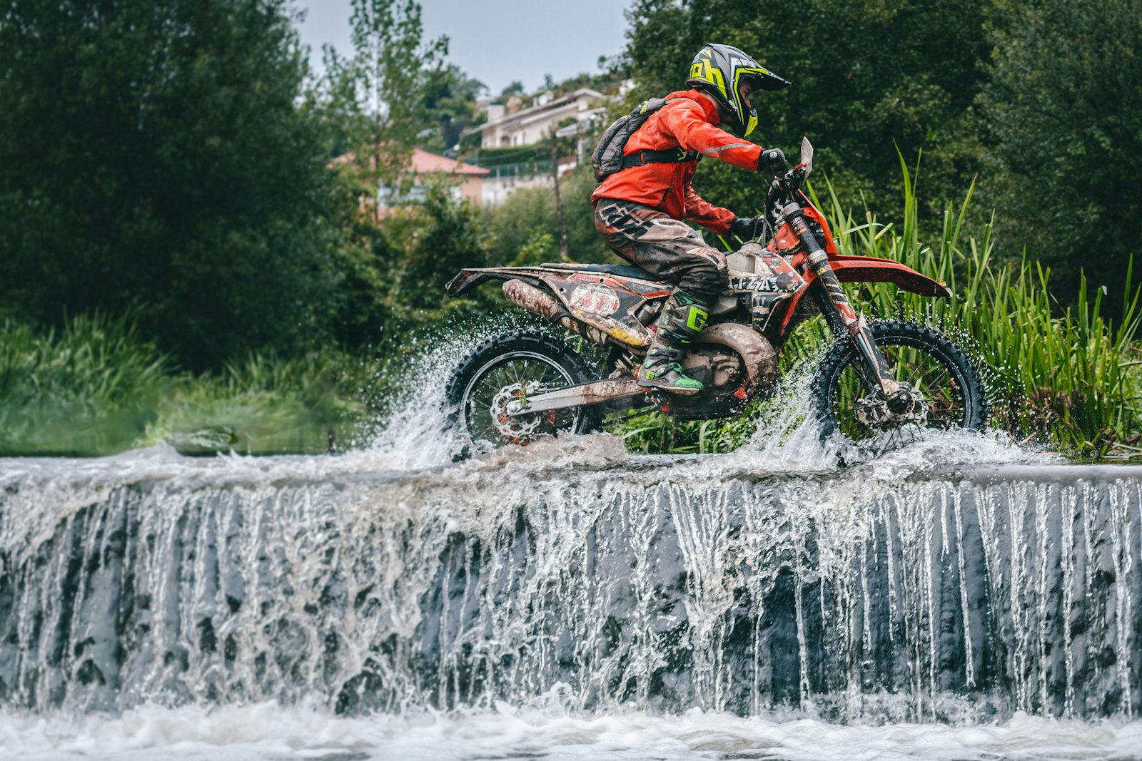 Pilote enduro franchissant une rivière sur une piste