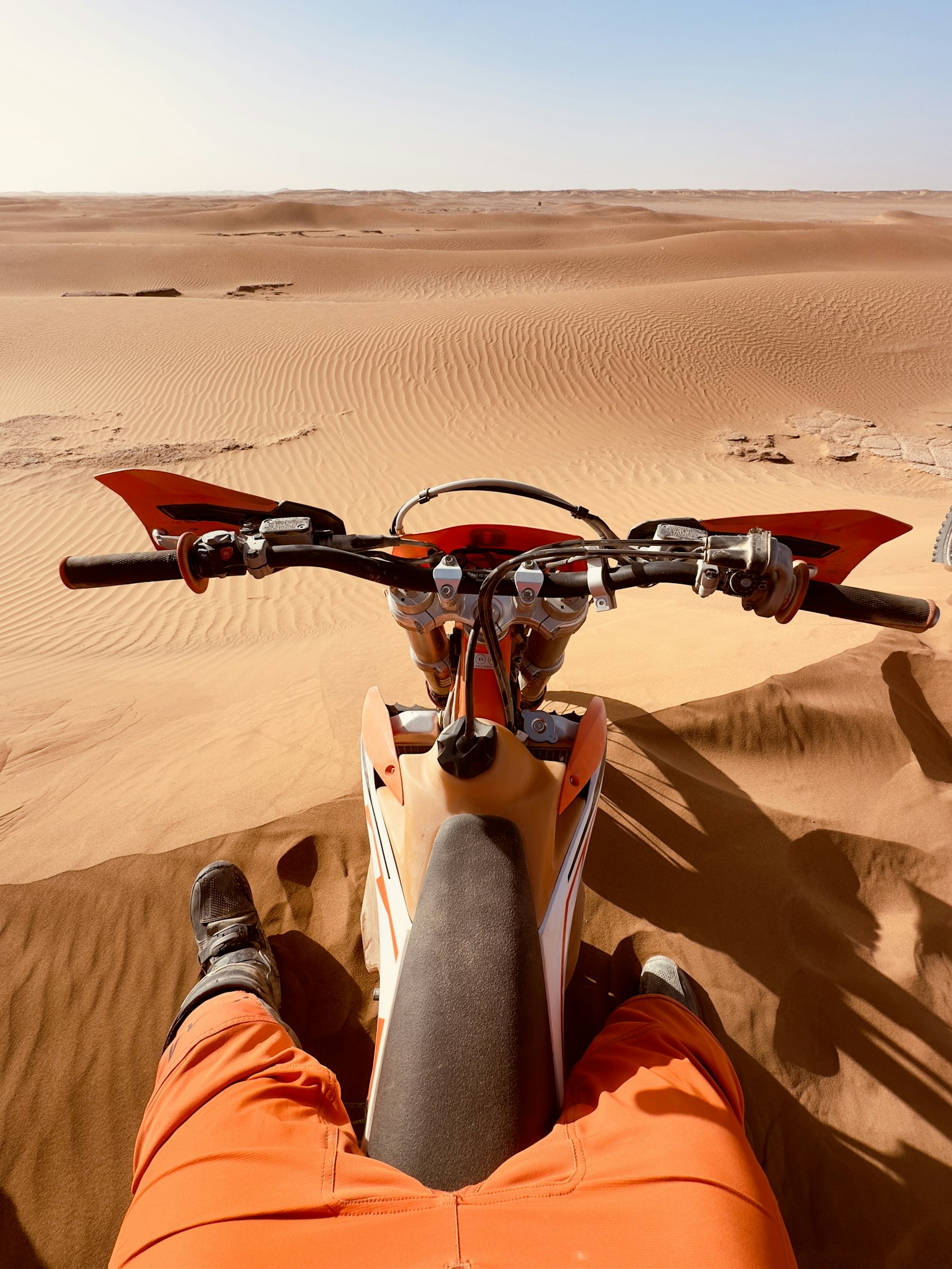 Pilote enduro dans les dunes du désert au coucher du soleil